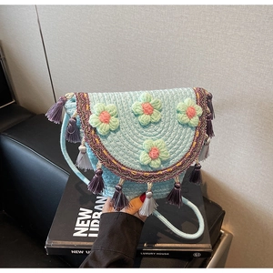 Detail of light blue woven bucket bag with ethnic fringe and 3D floral accents