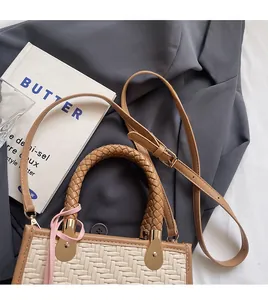Détail du sac à main tissé crème avec bordure en cuir marron sur une veste de blazer sombre