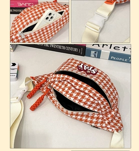 Détail du sac bandoulière orange à motif pied-de-poule avec broderie STAY et zips