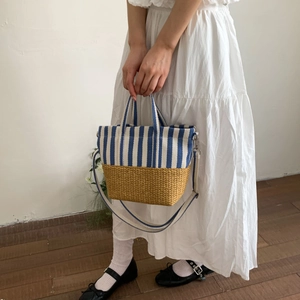 Lifestyle view of canvas straw tote bag with blue stripes and detachable strap on model