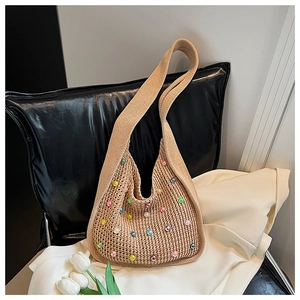 Detail view of a woven tote bag featuring colorful faux pearls and a chunky knit texture