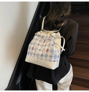 Détail du sac à dos imprimé ours et fleurs avec cordon de serrage sur modèle dans un escalier