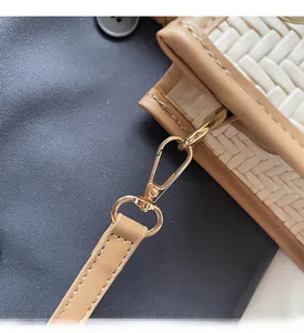 Détail de la texture tissée avec fermoir en métal doré et bordure en cuir beige sur le sac