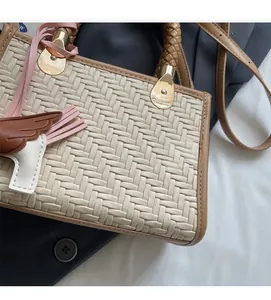 Détail du sac à main tissé avec quincaillerie dorée et breloque en cuir