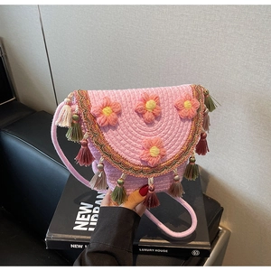 Detail of pink woven bucket bag featuring handmade crochet flowers and colorful tassels