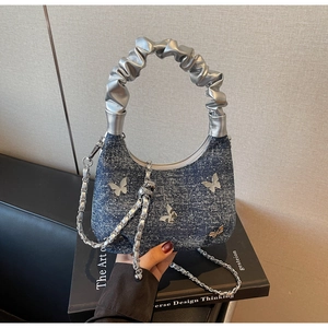 Close-up of blue denim hobo bag featuring silver butterfly accents and cloud handle