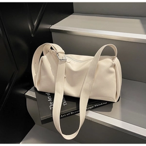 Detail einer beigen Zylindertasche mit verstellbarem Riemen auf grauen Stufen