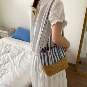 Detail of straw woven tote with blue striped canvas and adjustable strap in cozy room