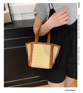 Detail of hand-held straw bucket bag with brown leather trim and handles for summer