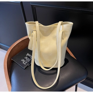 Detail of yellow oil wax leather bucket bag with crocodile texture and MER PAI logo