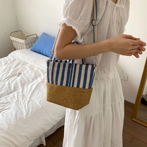 Detail of blue striped canvas and straw patchwork on a handheld tote beach bag