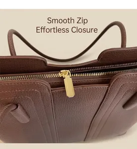 Gros plan sur la fermeture éclair dorée et les coutures du sac en cuir marron