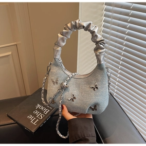 Detail of light blue denim dumpling bag with silver butterfly and rhinestone accents