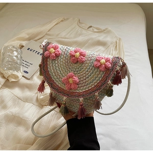 Close-up of woven bucket bag with 3D pink flowers and colorful tassel details