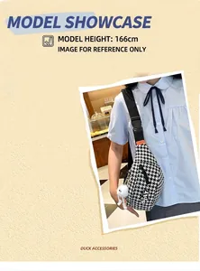 Détail du sac bandoulière pied-de-poule avec logo STAY et breloque en peluche blanche