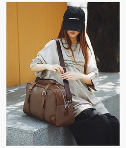 Detail of vintage brown textured leather boston bag with wide canvas shoulder strap