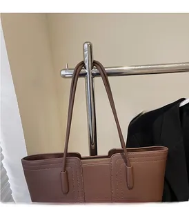 Détail des anses longues confortables et cuir grainé robuste du sac fourre-tout brun