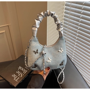 Detail of light blue denim handbag with silver butterfly applique and rhinestone accents
