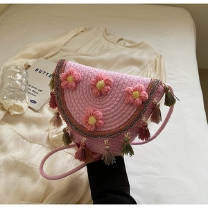 Detail of pink woven straw bucket bag with crochet flowers and colorful tassels