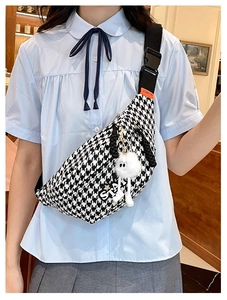 Détail du sac bandoulière pied-de-poule avec texte 'STAY' et pendentif en peluche