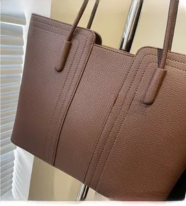 Gros plan du sac cabas marron en cuir grainé avec fermeture éclair et fines anses