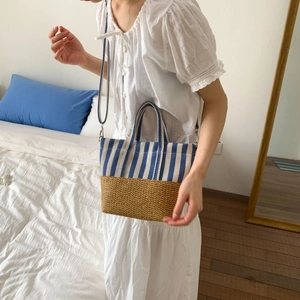 Detail of blue striped canvas and straw patchwork handbag with adjustable strap