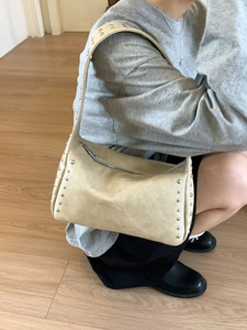 Schicke beige Unterarmtasche mit Silbernieten und Vintage-Lederstruktur an Model