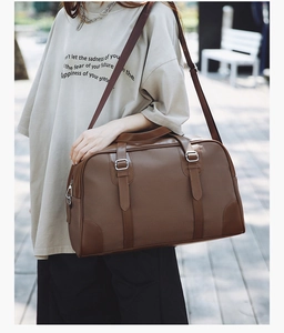 Macro view of dark brown leather Boston bag showing lychee grain texture and wide strap