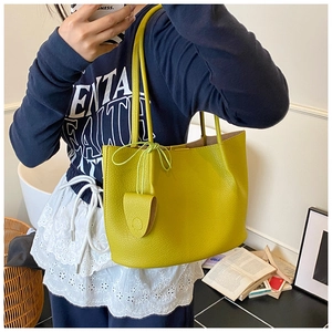 Detail of yellow lychee grain leather tote bag with leaf pendant and slender shoulder straps