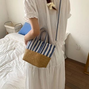 Detail of canvas stripe and straw patchwork bag with detachable strap in bedroom setting