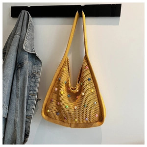 Detail of yellow knit beach bag with colorful beads hanging on a wall hook