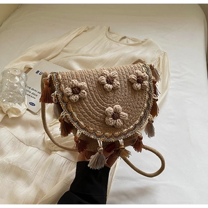 Detail of woven straw crossbody bag with knitted flowers and fringe tassels