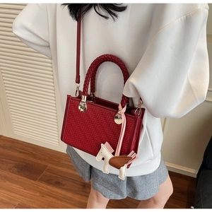Détail du sac à main rouge tissé avec pendentif pégase blanc et ferrures dorées