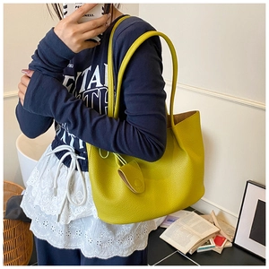 Detailed close-up of bright yellow lychee pattern leather tote bag with a small charm