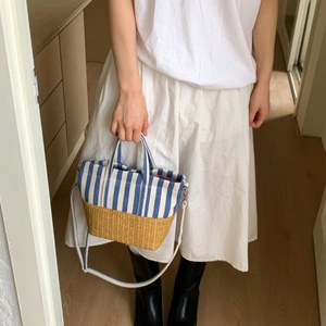 Detail of blue striped canvas and straw tote bag shown on model for daily casual wear