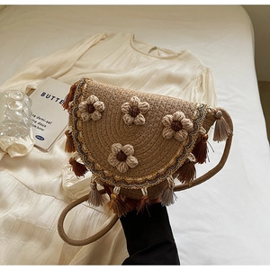 Detail of woven straw bucket bag showing 3D crochet flowers and fringe tassels