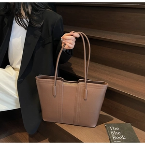 Détail du sac cabas en cuir marron montrant le grain de litchi et la fermeture éclair