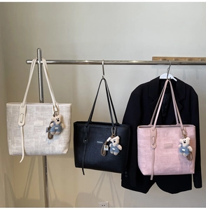 Detailed texture of woven tote bags in beige, black, and pink with cute bear pendants