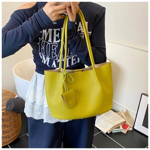 Detailed view of ginger yellow tote bag with pebble leather texture on model's shoulder