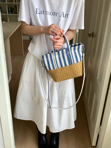 Detail of canvas striped stitching and straw woven texture on a casual tote bag