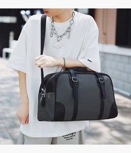 Detailed view of large grey woven travel bag with black leather trim and metal buckles