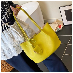 Detailed close-up of a lime yellow litchi texture tote bag with leather tag detail