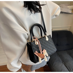 Détail du sac à main noir tressé avec breloque Pégase en cuir et boucle en métal doré