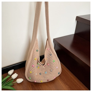 Close-up of beige knit hobo bag featuring colorful macaron pearls and mesh hollow texture