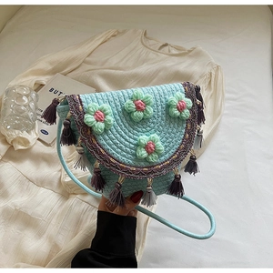 Detail of light blue woven bucket bag with 3D crochet flowers and fringe trim edges