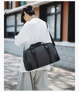 Deep grey large capacity travel bag with leather trim worn on shoulder in outdoor city street