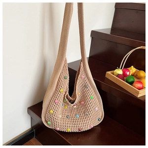 Detail of beige knit tote bag with colorful pearl beads on textured crochet fabric