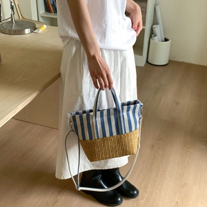Detailed view of striped canvas and woven straw tote bag with adjustable shoulder strap