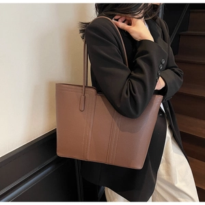 Détail du sac cabas en cuir caramel montrant le grain de galets et les doubles coutures