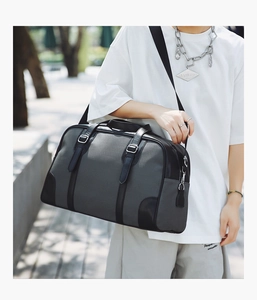 Detail of grey fabric travel bag with black leather trim and silver metal buckles